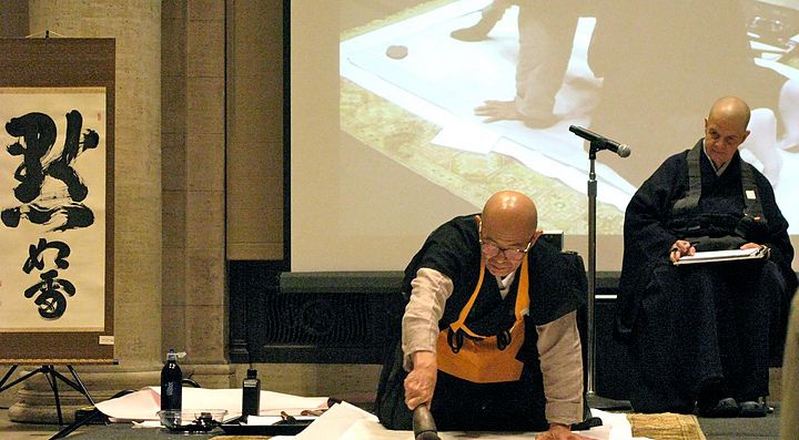 Monaci giapponesi eseguono una dimostrazione di calligrafia tradizionale.