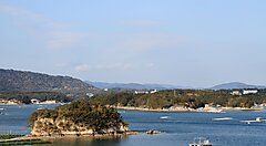 Baia di Ago con isole alberate e mare calmo al tramonto.