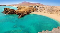 Spiaggia con acque turchesi e montagne a Lanzarote.