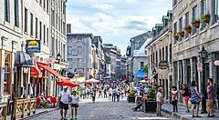 Strada pedonale affollata nel centro di Montreal, con negozi e ristoranti.