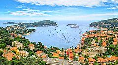 Vista panoramica della costa di Nizza con la baia e numerose imbarcazioni.