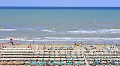 Spiaggia di Riccione con lettini e ombrelloni allineati vicino al mare.