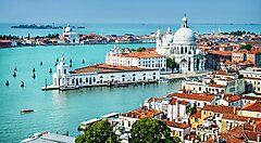 Canali di Venezia con monumenti storici e cupole sullo sfondo.