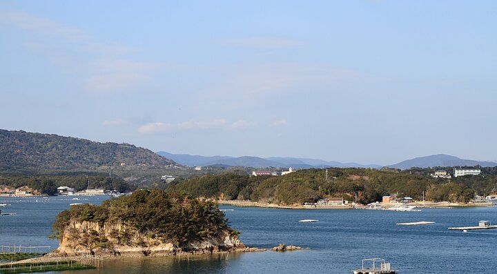 Baia di Ago con isole alberate e mare calmo al tramonto.