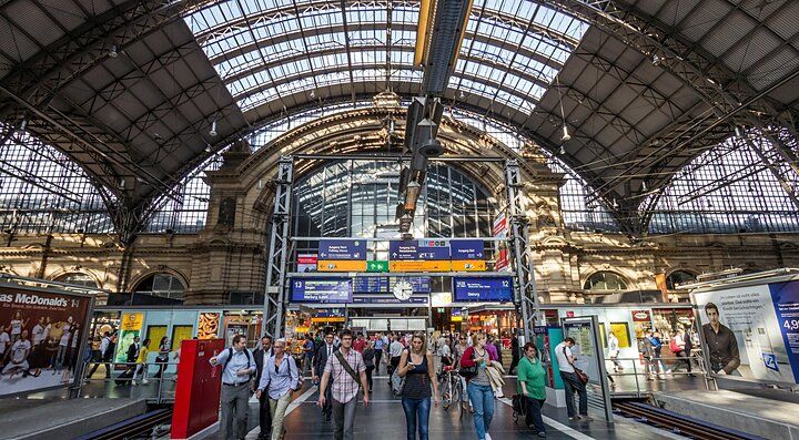 Stazione ferroviaria di Francoforte affollata con viaggiatori.