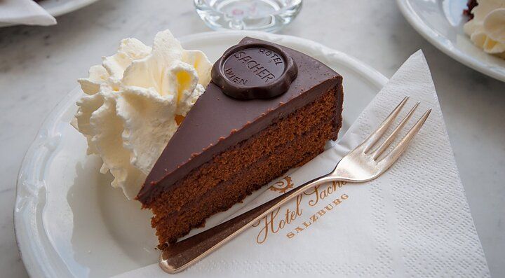 Fetta di Sachertorte austriaca con panna su un piatto.