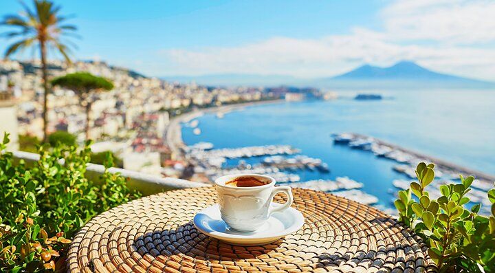 Tazza di caffè su un tavolo con vista su Napoli e il Vesuvio.