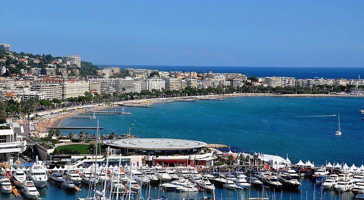 Vista della costa e del porto di Cannes con yacht e palazzi sullo sfondo.