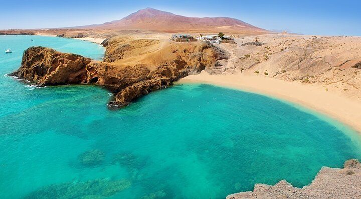 Spiaggia con acque turchesi e montagne a Lanzarote.