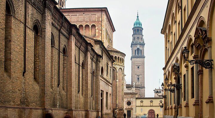Strada con edifici storici e campanile nel centro di Parma.