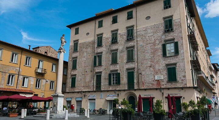 Edifici storici e una piazza a Pisa con un cielo azzurro.