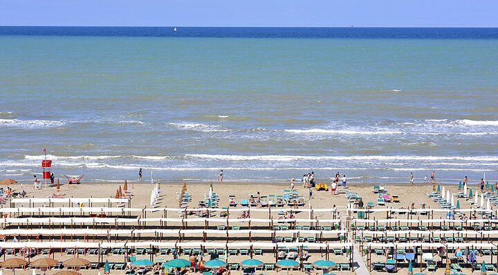 Spiaggia di Riccione con lettini e ombrelloni allineati vicino al mare.