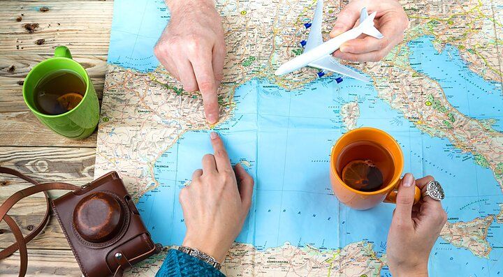 Due mani indicano una mappa con una macchina fotografica e due tazze.