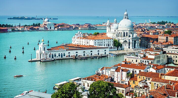 Canali di Venezia con monumenti storici e cupole sullo sfondo.