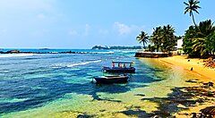 Spiaggia tropicale in Sri Lanka con palme e barche sul mare.