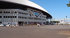 L'Ariake Coliseum a Tokyo con persone che camminano all'esterno.