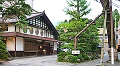 Ingresso di un tradizionale ryokan ad Awazu Onsen, circondato da alberi.