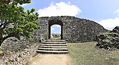 Rovine del Castello di Nakagusuku con arco di pietra e vegetazione.