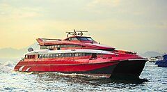 Traghetto rosso naviga verso Macao al tramonto.