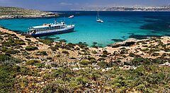 Barca e coste rocciose con mare cristallino a Malta.