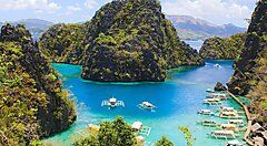 Laguna turchese di Boracay con barche tradizionali e colline verdi.
