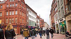Persone passeggiano in una via commerciale di Dublino.
