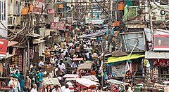 Strada affollata e vivace a Nuova Delhi con bancarelle e persone.
