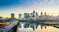 Skyline di Philadelphia con un fiume e strade trafficate al tramonto.