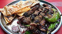 Piatto albanese con carne grigliata, pane e verdure.
