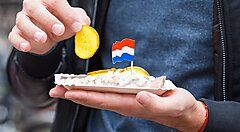 Snack olandese con bandierina e cetriolo in mano.