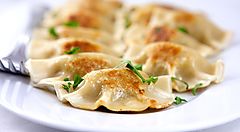 Pierogi polacchi su un piatto bianco con prezzemolo.