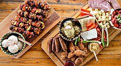 Piatti tradizionali rumeni su tavole di legno, tra carne, formaggi e verdure, su un tavolo rustico.