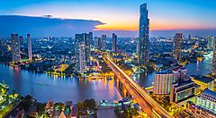 Skyline di Bangkok al tramonto con il fiume Chao Phraya e grattacieli illuminati.