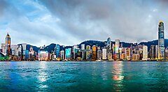 Lo skyline di Hong Kong visto dall'acqua sotto un cielo nuvoloso.