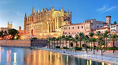 La cattedrale di Palma a Maiorca riflessa sul mare al tramonto.
