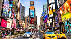 Strada trafficata a Times Square, New York, con taxi gialli e cartelloni luminosi.