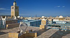 Vista di Tunisi con torre e terrazza ornata da piastrelle e ringhiere blu.