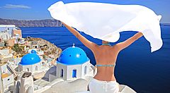 Donna ammira il paesaggio di Santorini con mare e cupole blu sullo sfondo.