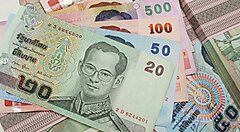 Banconote thailandesi di diversi tagli sparse sul tavolo.