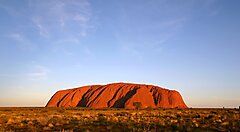 Uluru, l'iconico monolito rosso in Australia illuminato dalla luce del tramonto.