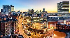 Panorama urbano di Manchester al tramonto con edifici e strade.