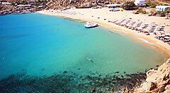 Spiaggia con ombrelloni e mare turchese a Mykonos.