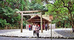 Un santuario tradizionale giapponese circondato da alberi e visitatori.