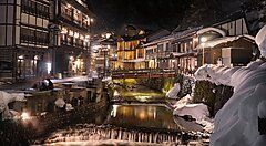 Strada illuminata di Ginzan Onsen con edifici tradizionali e neve.