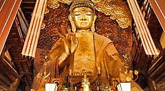 La statua del Grande Buddha di Gifu, ornata e dorata, all'interno di un tempio.