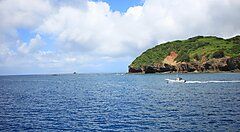 Il mare di un'isola verdeggiante a Chichijima con una barca in lontananza.