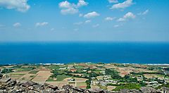 Veduta dell'Isola di Kume con campi coltivati e mare all'orizzonte.