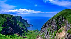 Paesaggio costiero dell'isola Rebun con colline verdi e mare.