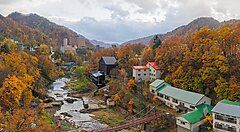 Jozankei Onsen in autunno, con alberi colorati e edifici vicino al fiume.