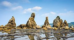 Rocce giganti lungo la costa di Kushimoto, Giappone, sotto un cielo azzurro.